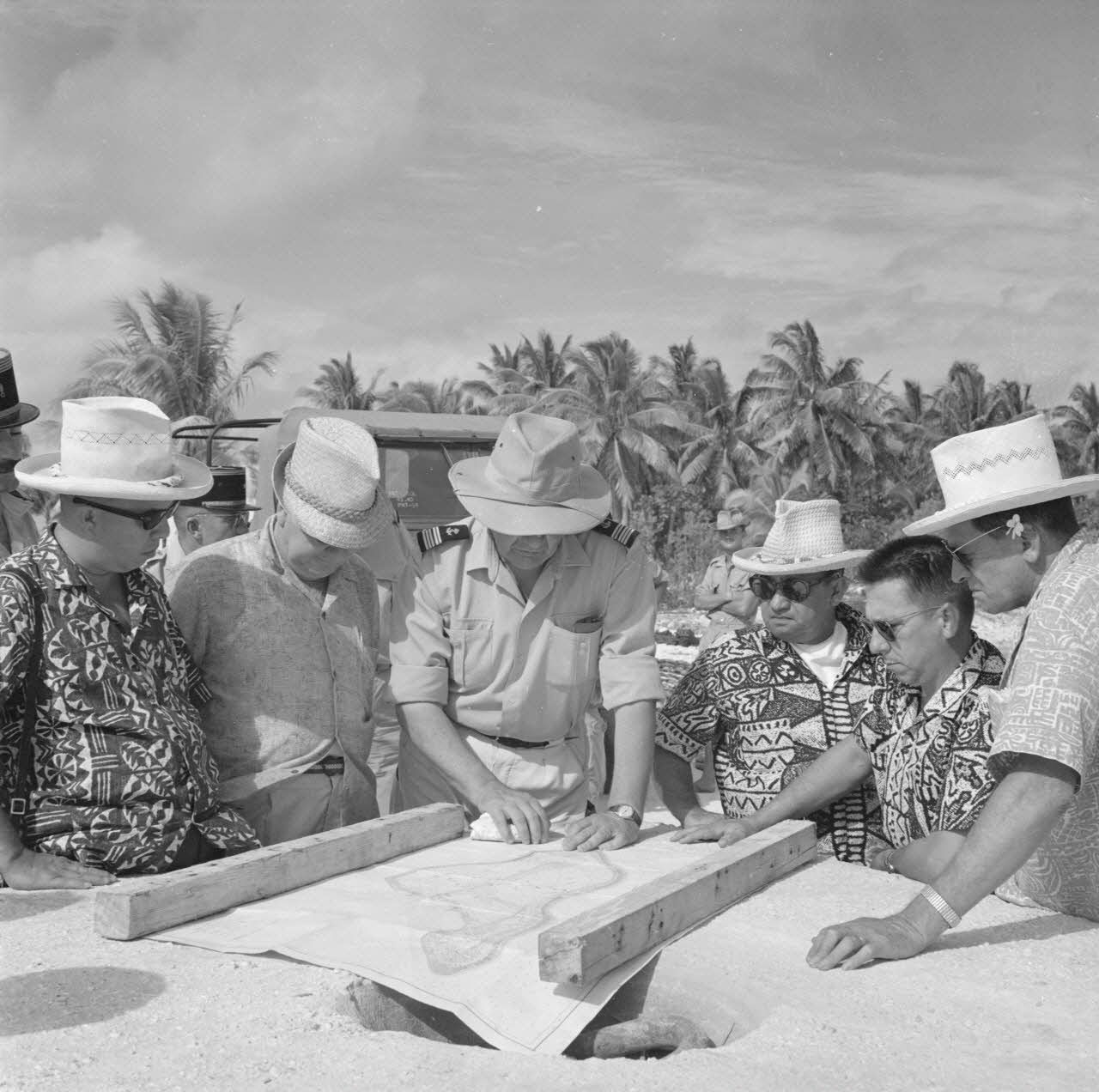 Des élus polynésiens, dont Jacques Tauraa et Alfred Poroi à gauche d’un capitaine de vaisseau, écoutant un exposé de ce dernier sur les installations du CEP, Moruroa, avril 1964.